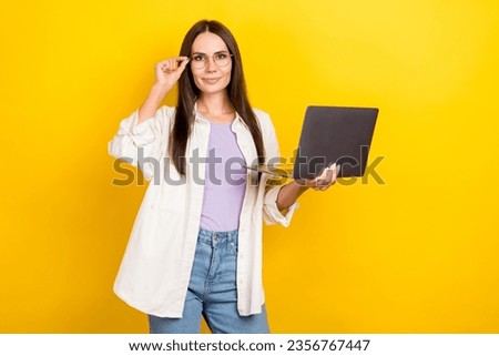 Photo portrait of lovely young lady hold netbook smm manager touch specs wear trendy white garment isolated on yellow color background