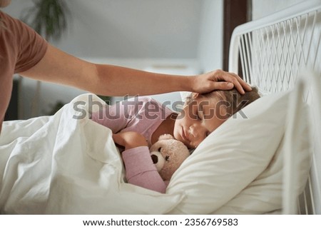Mother taking care of her ill sleeping daughter at home Royalty-Free Stock Photo #2356769583