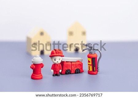 Close-up a firefighter model, fire extinguisher, fire truck with a background of wooden house. home fire, Property insurance concept, Emergency protection for safety and rescue in the building.