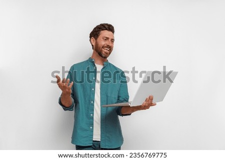 Handsome smiling man with laptop talking via video call over white background