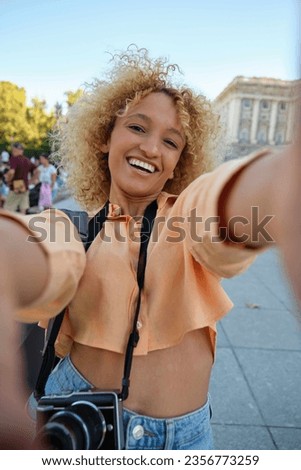 Latin female tourist smiling and doing a selfie while sightseeing in Madrid, Spain.