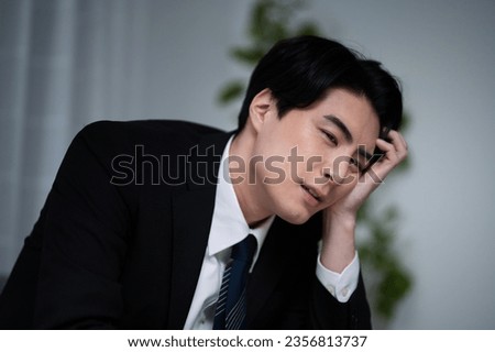 A Japanese male salaryman who is tired of working overtime and coming home late and is thinking about changing jobs. Royalty-Free Stock Photo #2356813737