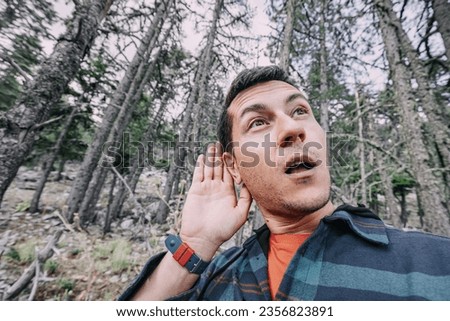 A frightened and lost male hiker heard some rustling in the forest and took it for a wild animal or a bear looks around in the forest. Royalty-Free Stock Photo #2356823891