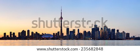 Toronto city skyline silhouette panorama at sunset over lake with urban skyscrapers.