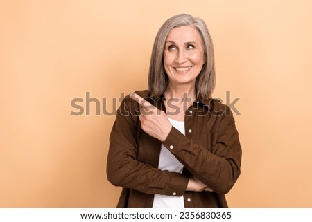 Portrait of satisfied friendly person wear stylish jacket indicating look at empty space service isolated on beige color background