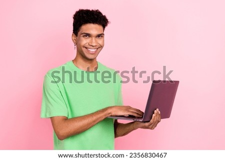 Photo of cheerful positive man dressed green t-shirt communicating modern device isolated pink color background