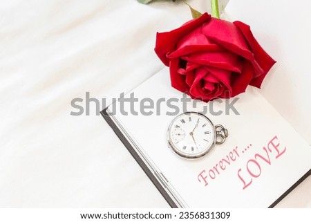 Fresh beautiful red rose with vintage watch on blank white notebook on white bed sheet background, love and romance concept, valentine background idea, forever love
