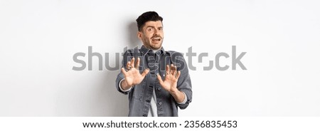 Stay away from me. Scared young man screaming and asking to stop, step back and look frightened, rejecting something bad, standing on white background. Royalty-Free Stock Photo #2356835453