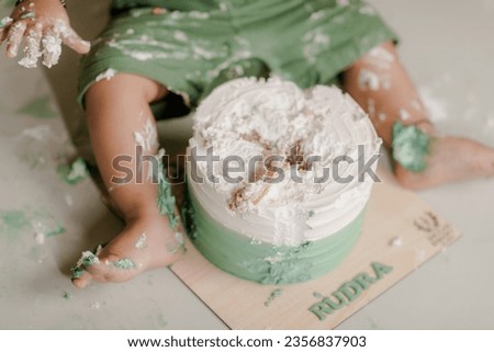 Smashed cake on white table for first birthday. Messy pieces