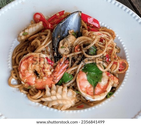 a photography of a bowl of pasta with shrimp and musselling, plate of pasta with shrimp, musselling, and other vegetables. Royalty-Free Stock Photo #2356841499
