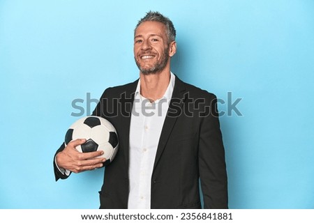 Football coach with soccer ball on blue studio backdrop