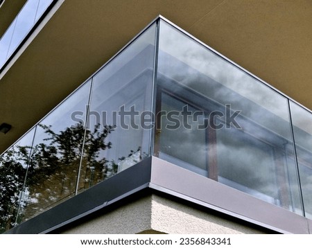 railing of a luxury house formed by glass panels fastened with metal stainless steel handles. gives an airy impression. polished metal cover on a greenhouse terrace window, reflection Royalty-Free Stock Photo #2356843341