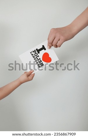 a woman's hand and a child's hand hold a card with the inscription I love the Polish language Royalty-Free Stock Photo #2356867909