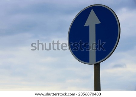 Road sign. Blue, circular right turn traffic sign. Road Sign Against Cloudy Sky. Directional road sign with blue sky background. 