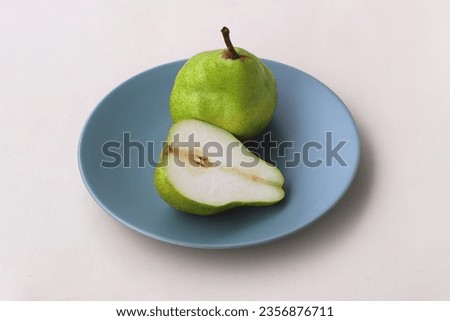 Pear and half cut of pear served on plate, isolated on white background