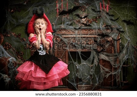 A little pretty girl in a pirate costume stands in an old castle with cobwebs and the bats and is very frightened. Halloween party at the haunted castle. Place for text. Royalty-Free Stock Photo #2356880831
