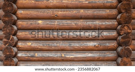 A log wall construction with a swedish cope log profile. Dirty and heavily cracked brown wall of a blockhouse as a natural rural background Royalty-Free Stock Photo #2356882067