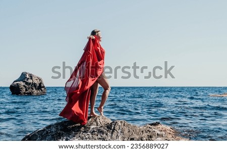 Woman travel sea. Happy tourist in long red dress enjoy taking picture outdoors for memories. Woman traveler posing on beach at sea surrounded by volcanic mountains, sharing travel adventure journey
