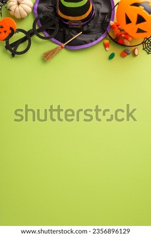 Enthralling kids' Halloween night celebration idea. Overhead vertical shot of sweets, witch hat and Halloween-themed embellishments on an isolated green setting, allowing space for adverts or text