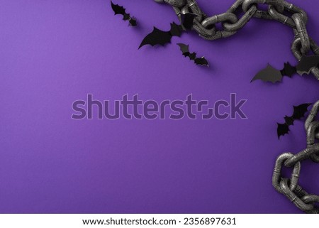 Spooky Halloween gathering concept. Bird's-eye top view picture highlighting black paper bats Halloween-themed chains on a purple isolated background with ample copyspace for text or advertising
