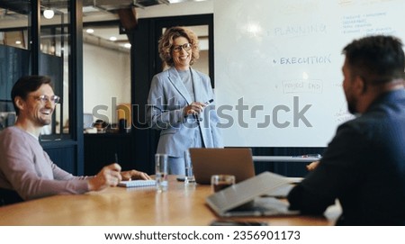 Group of professionals having a discussion in a meeting. Business woman stands in a boardroom and doing a presentation. Happy business team planning a project in an office. Royalty-Free Stock Photo #2356901173