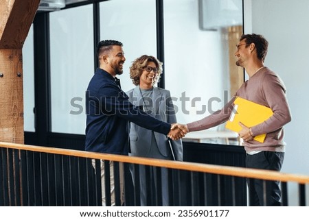 Successful business men shaking hands over a promotion in an office. Happy business professionals reaching an agreement on an internal recruitment deal. Royalty-Free Stock Photo #2356901177
