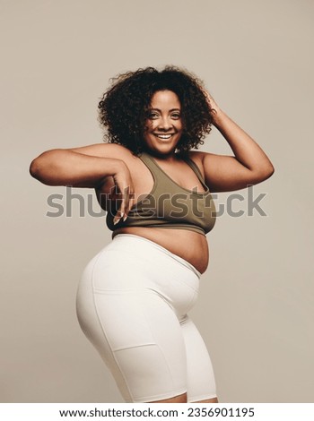 Confident plus size woman dancing in a studio, enjoying herself and having fun with her body. Happy woman in fitness clothing expressing her sense of self with body movements. Royalty-Free Stock Photo #2356901195