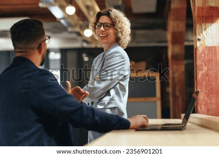 Tech professionals talking to each other in a coworking office. Two business people having a conversation in a workplace. Royalty-Free Stock Photo #2356901201