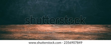 Black blank used chalkboard background, texture. Empty horizontal blackboard for backdrop and vintage wooden desk. Banner, copy space