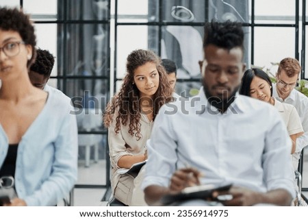 Multi-ethnic group of people while answering questions during training seminar or business conference in office, copy space