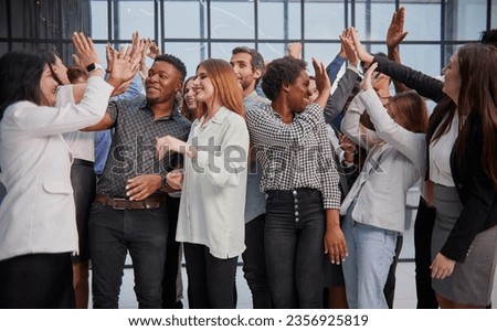 Excited multinational employees celebrating team victory giving high five gathered in office, Royalty-Free Stock Photo #2356925819