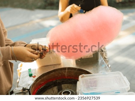 Cooking cotton candy in the park. Unrecognizable person preparing the cotton candy machine. Royalty-Free Stock Photo #2356927539