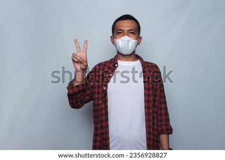 Asian young man wearing flannel shirt and medical mask. Air pollution concept.