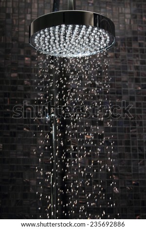 Luxury rain shower in domestic bathroom with falling water against Italian glass mosaics. The picture was taken with a high speed flash to freeze single drops.