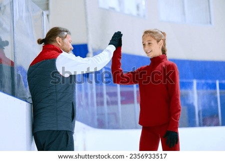 Success. Figure skating trainer, coach cheering his student, girl, giving high five. Ice rink arena background. Concept of professional sport, competition, sport school, health, hobby, ad