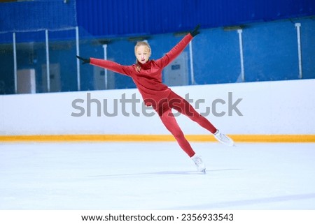 Concentration and motivation. Teen girl in red sportswear, figure skating athlete in motion on ice rink arena, training. Concept of professional sport, competition, sport school, health, hobby, ad