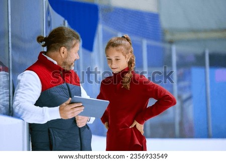 Girl, figure skating athlete with coach looking on tablet, learning techniques, watching videos on ice rink arena. Concept of professional sport, competition, sport school, health, hobby, ad