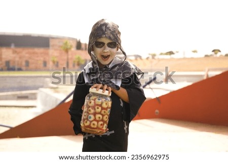 Happy halloween. Child in costume for halloween party holds in his hands a jar full of eyes. The boy is dressed as the living dead. Trick or treat.
