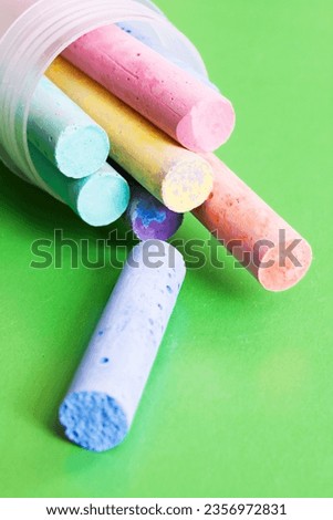 Container with multicolored crayons on a green background