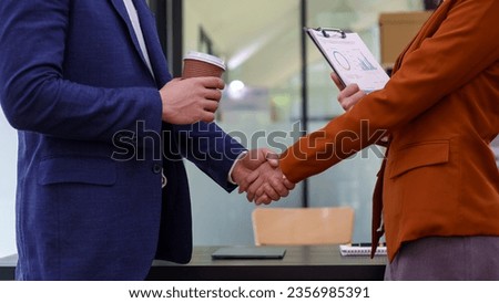 Two professional business people team woman and man workers working using digital tablet tech discussing business data standing at corporate office meeting.