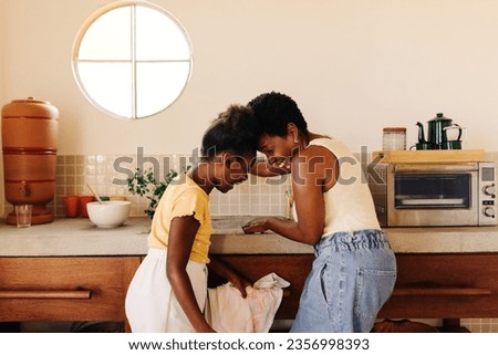 Happy mother and daughter bond over cleanliness and hygiene, washing hands in the sink with a clay filter for clean water. A quality time moment of parenting and motherhood in a Brazilian kitchen, Royalty-Free Stock Photo #2356998393