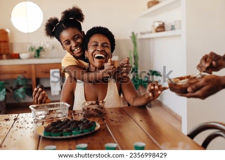 Mom and daughter having fun while prepare Brazilian brigadeiro, rolling the fudge balls together. Family enjoying quality time in the kitchen, creating sweet birthday treats and sharing happy moments. Royalty-Free Stock Photo #2356998429