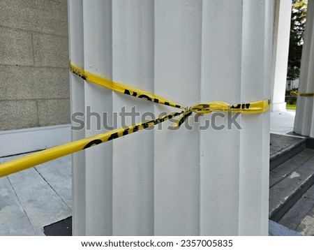 Caution tape wrapped around a large white pillar.