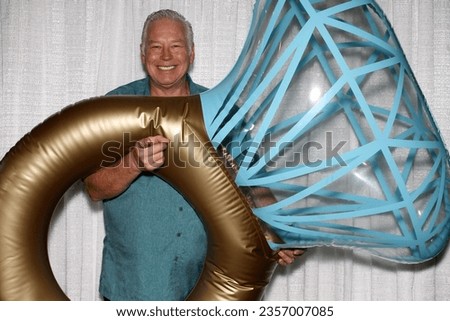 Wedding Ring. Photo Booth. A man smiles as he poses for his picture to be taken with a Giant Diamond Wedding Ring while in a Photo Booth at a Wedding Party. Wedding Parties Love a Photo Booth. Enjoy. 