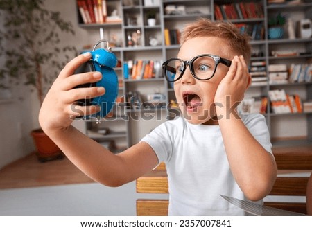 School boy dreaming with alarm clock in classroom Royalty-Free Stock Photo #2357007841