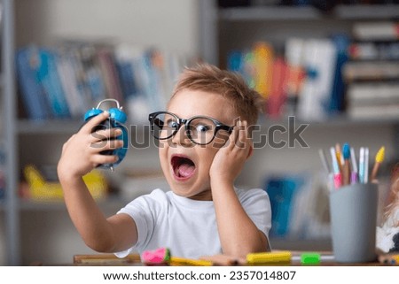 School boy dreaming with alarm clock in classroom Royalty-Free Stock Photo #2357014807