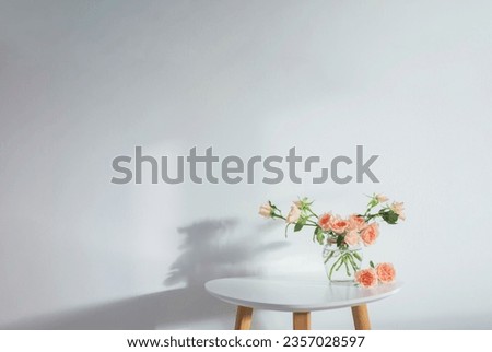 pink roses in glass jar on white modern table on background white wall