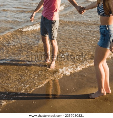 photo low angle view of young couple holding each other's hand standing near the sea