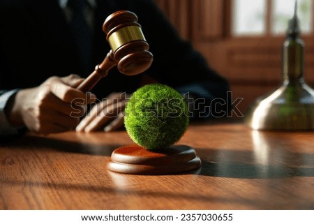 Hand of judge is hitting on earth with wooden gavel, Environmental law and international agreement about protocol for framework convention on climate change, world and environment sustainable concept. Royalty-Free Stock Photo #2357030655