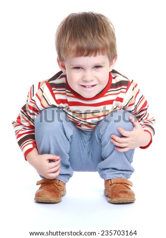 little boy sitting on his haunches and looking at the camera.White background, isolated photo.
